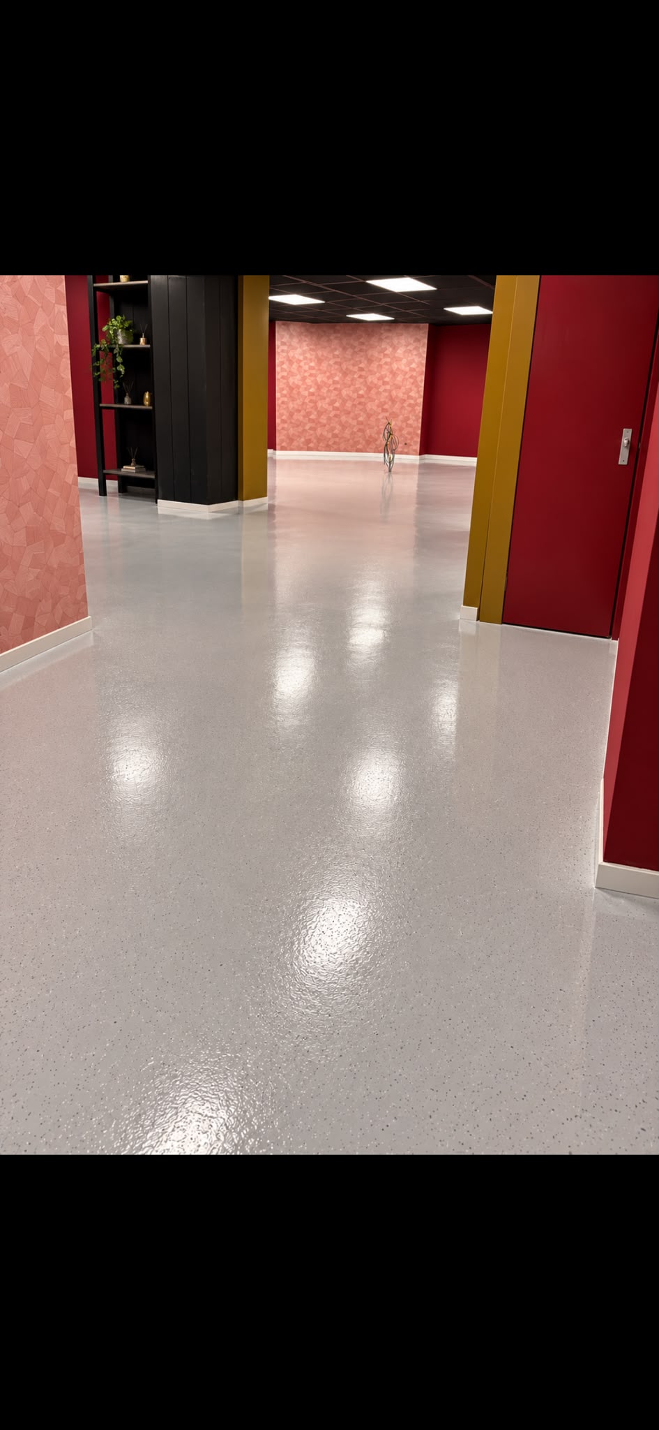 Grijze vloer met vlokkenafwerking tussen rode en roze wanden